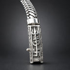 Silver bracelet with intricate designs on a wooden surface