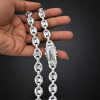 Silver chain held by a hand against a dark background