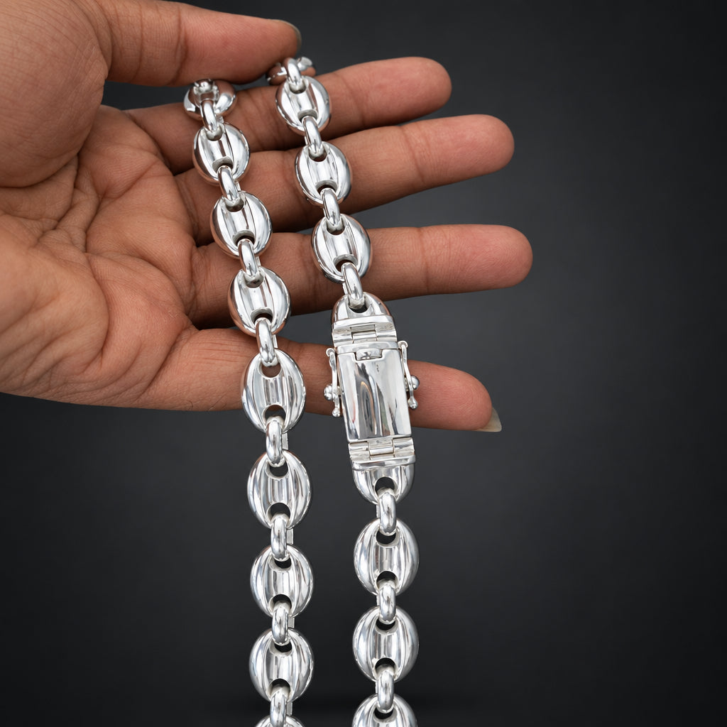 Silver chain held by a hand against a dark background
