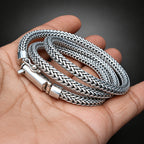 Three silver braided bracelets on a hand with a dark background