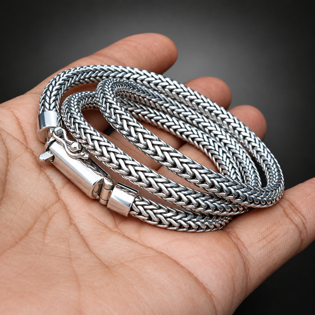 Three silver braided bracelets on a hand with a dark background