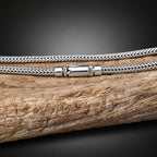 Silver braided cord with a clasp on a wooden surface