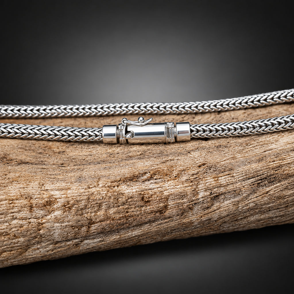 Silver braided cord with a clasp on a wooden surface