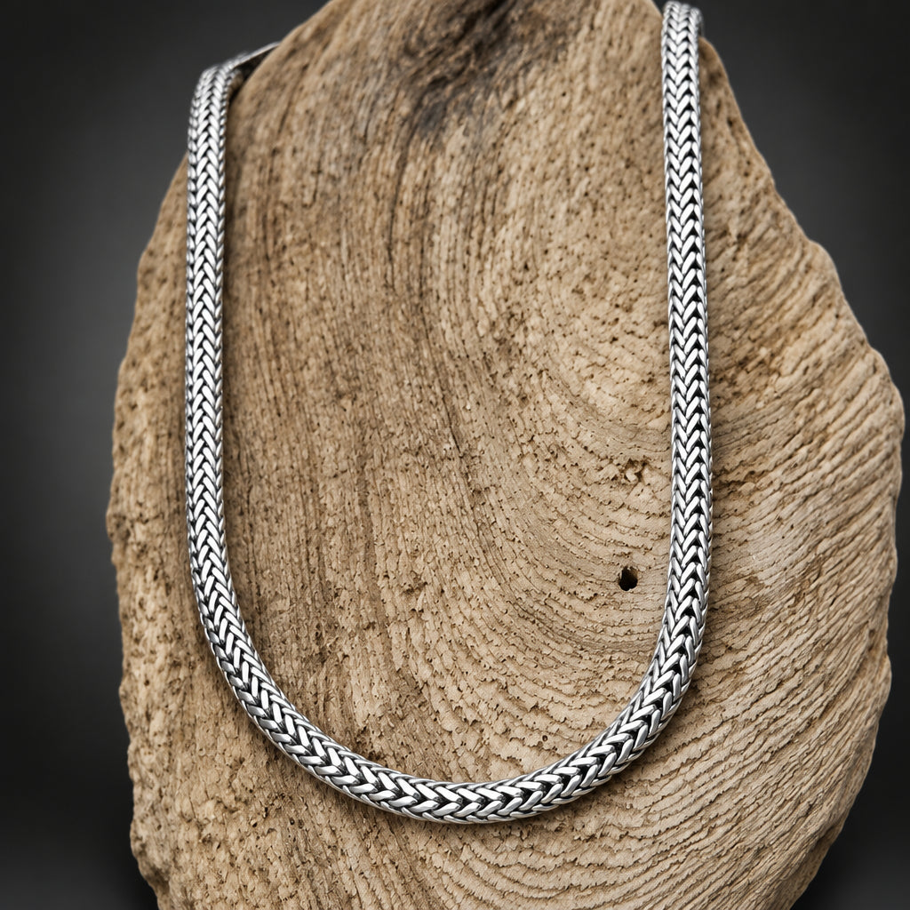 Silver braided necklace on a textured stone surface