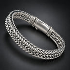 Silver braided bracelet with a magnetic clasp held in a hand against a dark background