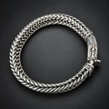 Silver braided bracelet on a hand against a dark background