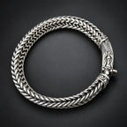 Silver braided bracelet on a hand against a dark background