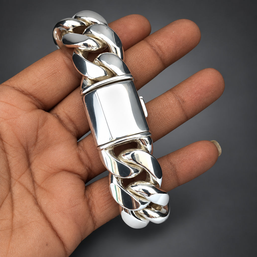 Silver bracelet held in a hand against a plain background