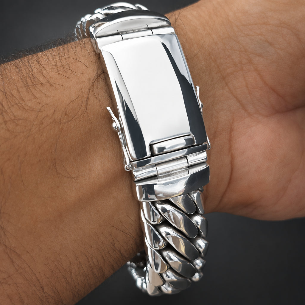 A close-up of a silver stainless steel link watch band being worn on a person's wrist, showing the polished clasp and textured links.