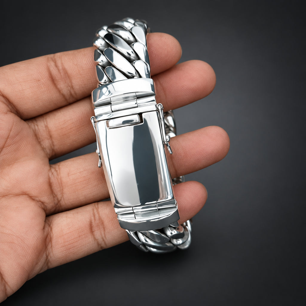 Silver decorative item held in a hand against a dark background