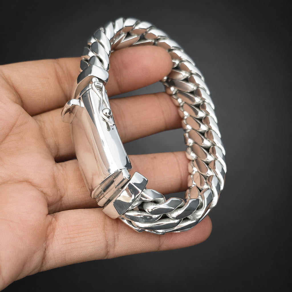 Silver bracelet held in a hand against a dark background