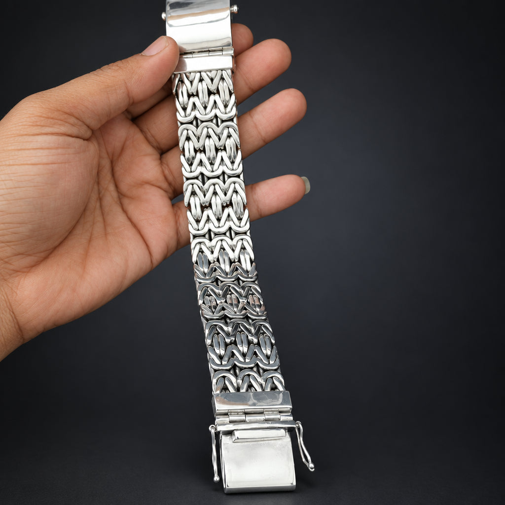 Silver watch strap held by a hand against a dark background