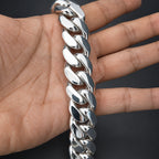 Silver chain bracelet on a person's wrist against a dark background