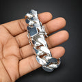 Silver chain bracelet held in a hand against a black background