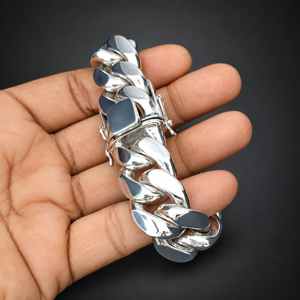 Silver chain bracelet held in a hand against a black background