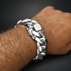 Silver chain bracelet on a wrist against a dark background