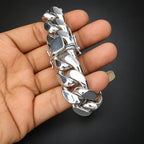 Silver chain bracelet held in a hand against a dark background