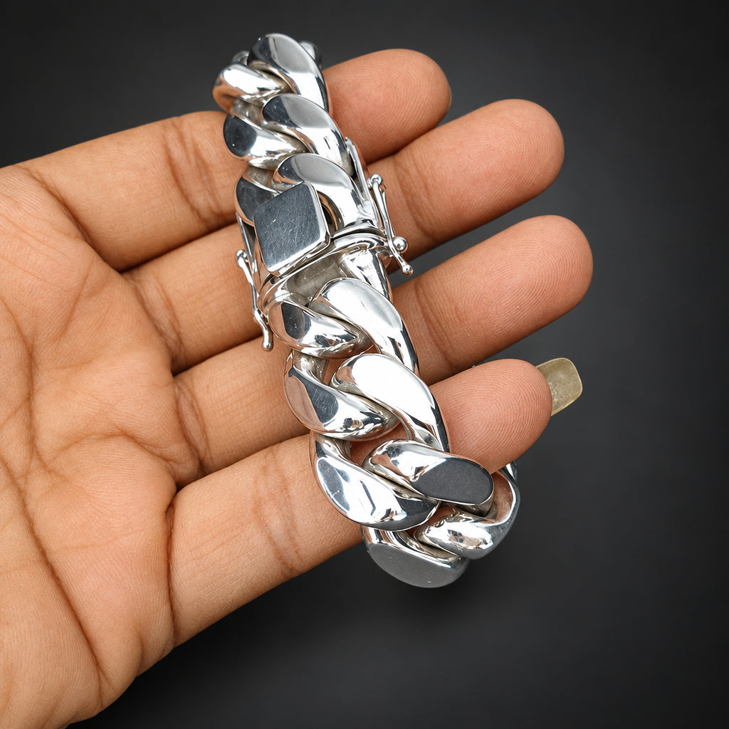 Silver chain bracelet held in a hand against a dark background