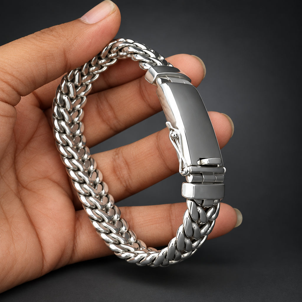 Silver chain bracelet held in a hand against a dark background