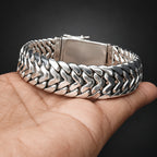Silver braided bracelet on a hand with a dark background