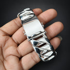 Silver belt buckle held in a hand against a dark background
