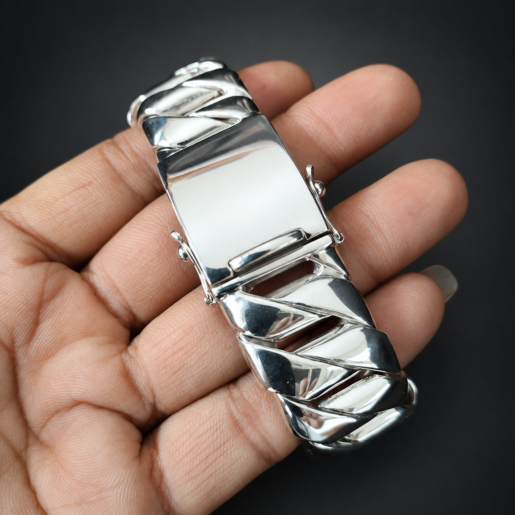 Silver belt buckle held in a hand against a dark background