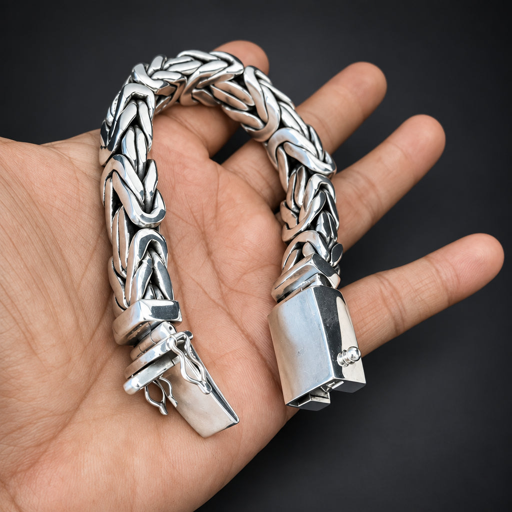 Silver chain bracelet on a hand against a dark background