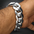 A close-up of a polished silver-tone Cuban link chain bracelet worn on a person's wrist.
