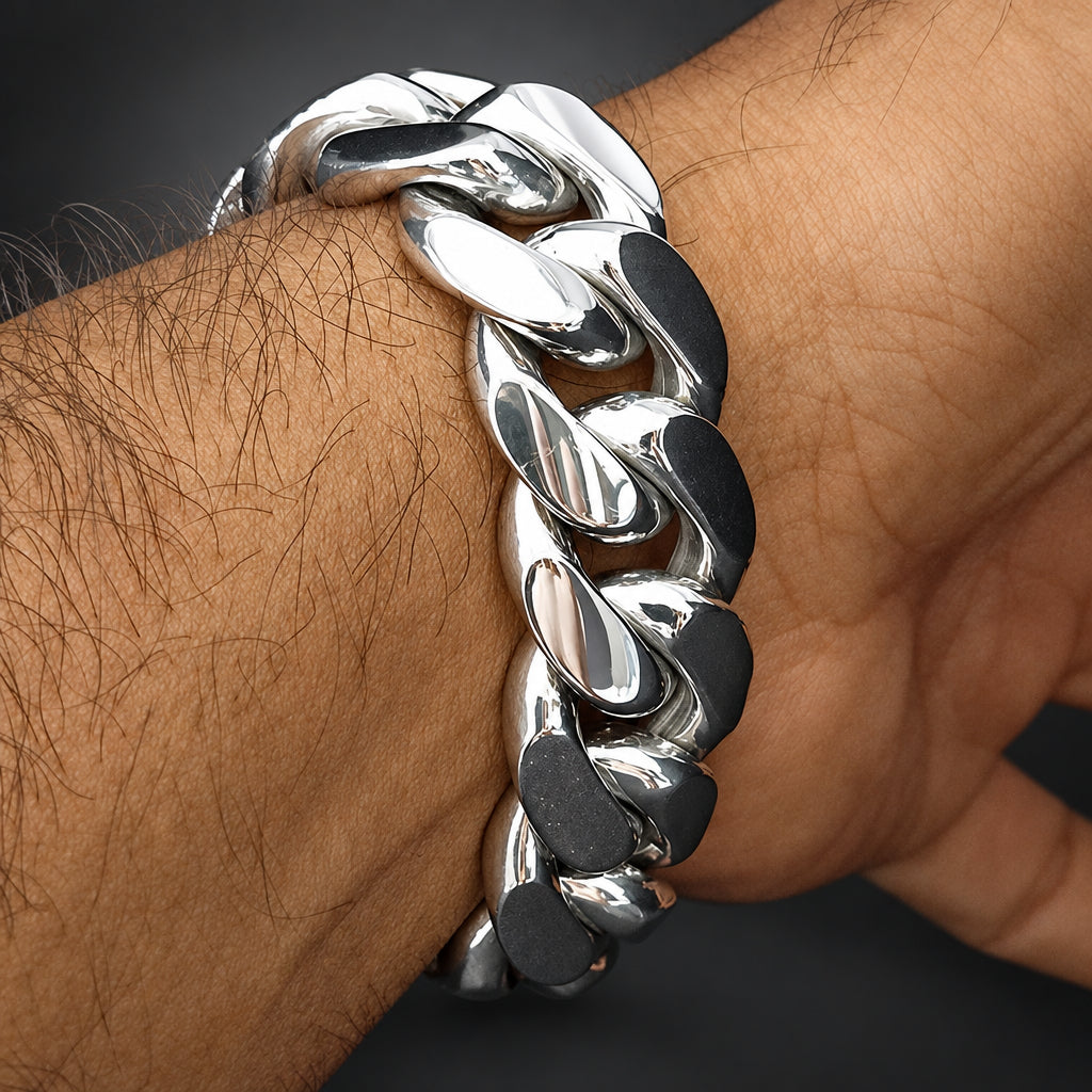 A close-up of a polished silver-tone Cuban link chain bracelet worn on a person's wrist.