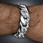Silver chain bracelet on a wrist with a neutral background
