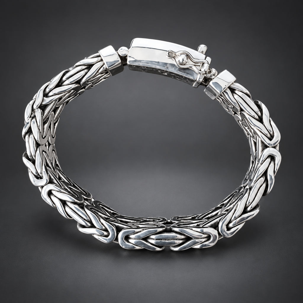 Silver braided bracelet held by a hand on a wooden surface with a dark background