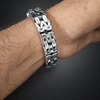 Silver chain bracelet on a wrist against a dark background