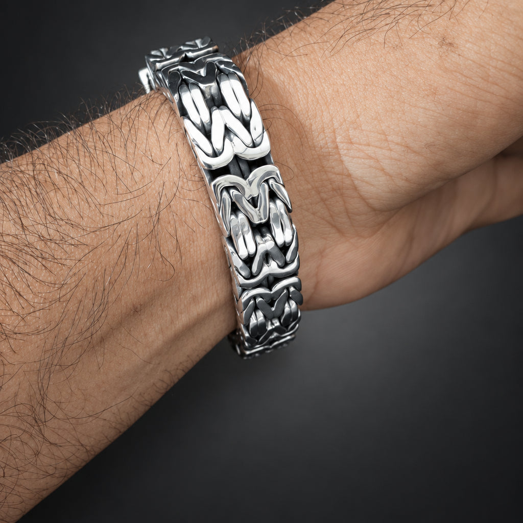 Silver chain bracelet on a wrist against a dark background