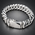 A chunky silver-toned metal chain bracelet with a clasp, shown resting on a person's hand against a dark background.