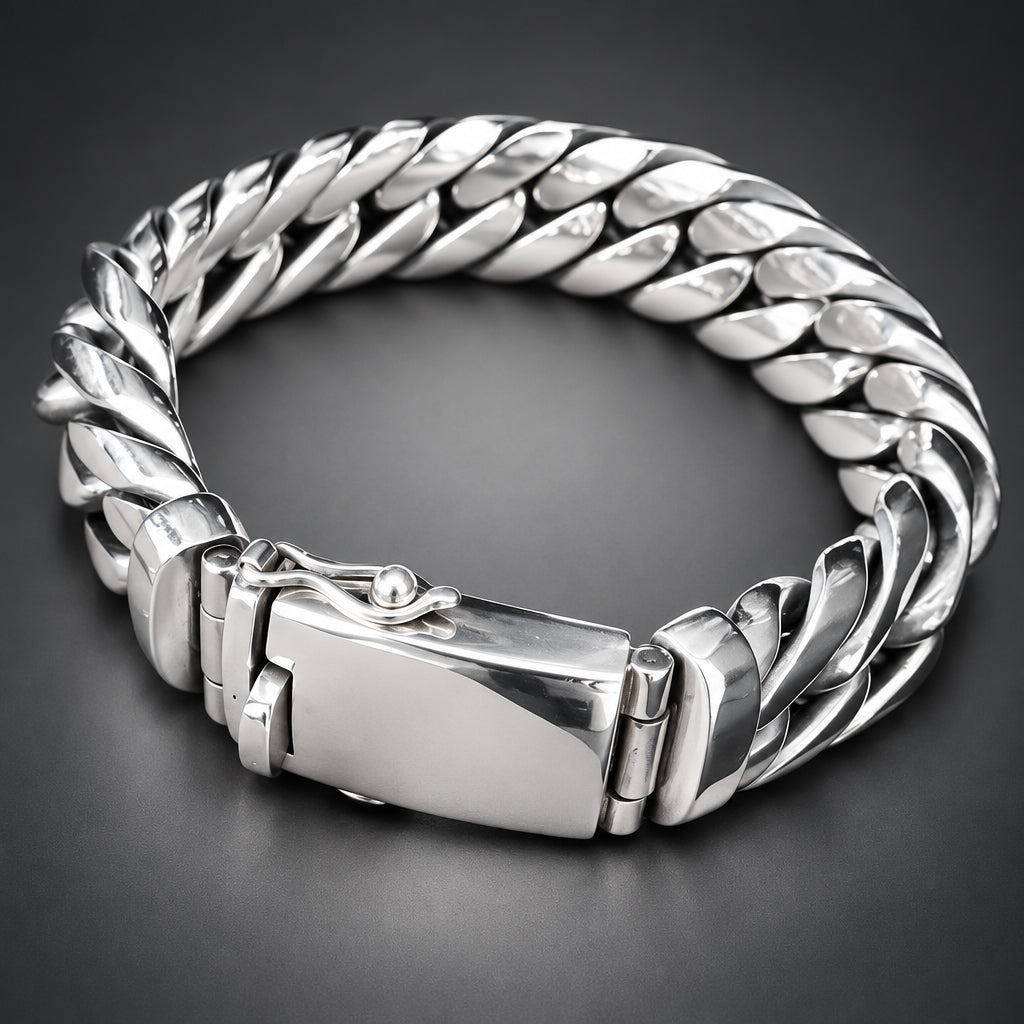 A chunky silver-toned metal chain bracelet with a clasp, shown resting on a person's hand against a dark background.