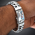 A close-up of a silver-toned metal link bracelet watch worn on a person's wrist.