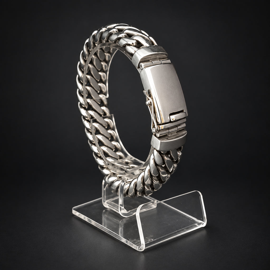A silver stainless steel Cuban link chain watch band displayed on a clear acrylic stand against a dark black background.