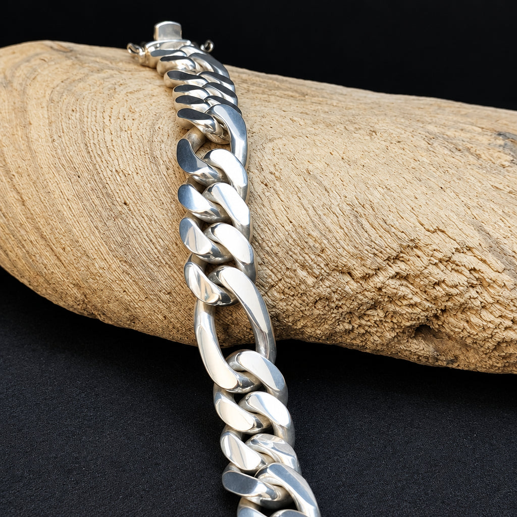 Silver chain bracelet on a wooden log with a black background