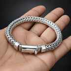 Silver braided bracelet on a hand with a dark background