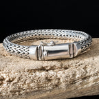 Silver braided bracelet on a wooden surface with a dark background