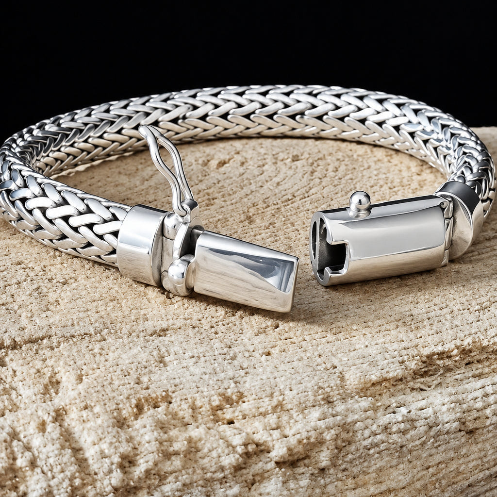 Silver braided bracelet with clasp on a wooden surface