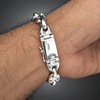 Silver bracelet on a wrist with a plain background