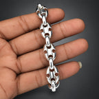 Silver chain bracelet held in a hand against a plain background