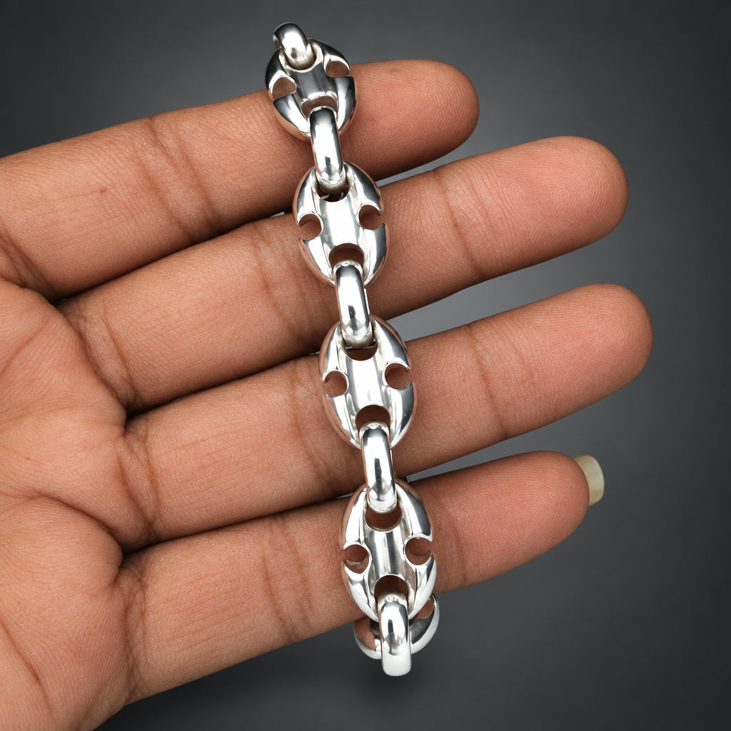 Silver chain bracelet held in a hand against a plain background