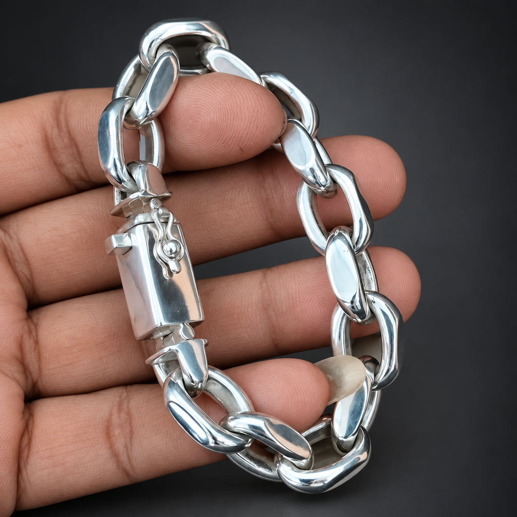 Silver chain bracelet held by a hand against a dark background