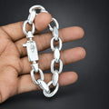 Silver chain bracelet held by a hand against a dark background