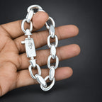 Silver chain bracelet held by a hand against a dark background
