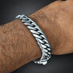 Silver chain bracelet on a wrist with a dark background