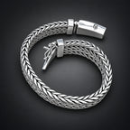 Silver braided bracelet on a hand with a dark background