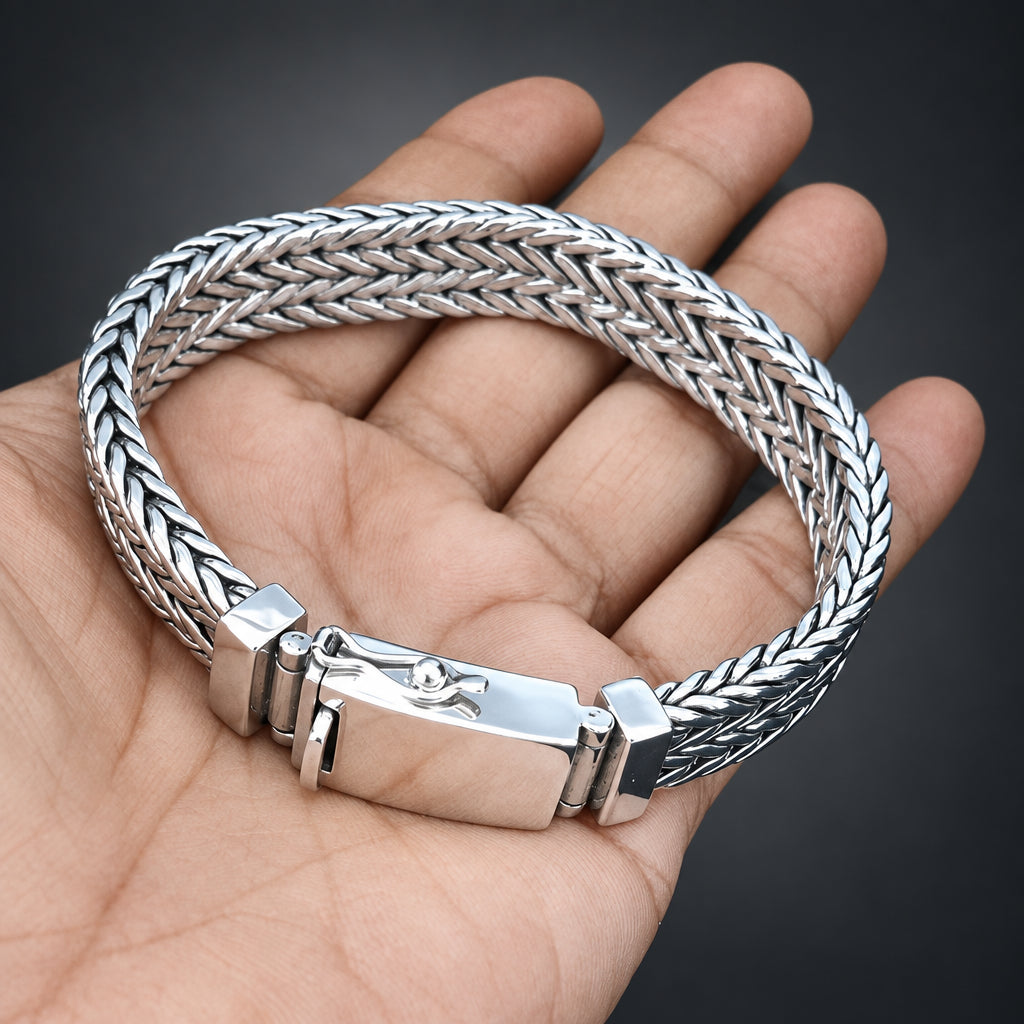 Silver braided bracelet on a hand with a dark background